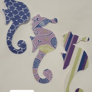 May include: A pack of three fabric seahorse shapes. The seahorses are in a purple, blue, and green color scheme with various patterns. The text "Pack 47" is printed on the white background.