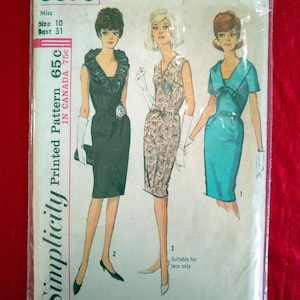May include: Vintage Simplicity sewing pattern number 5670 for a dress. The pattern is for size 10, bust 31 inches, and costs 65 cents. The pattern shows three different styles of dresses: a black dress with a ruffled collar, a patterned dress with a V-neck, and a turquoise dress with a bow.