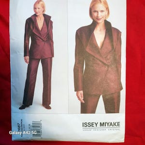 May include: A sewing pattern featuring a burgundy suit with a jacket and pants. The jacket has a unique collar and a single button closure. The pattern includes the text "ISSEY MIYAKE" and "VOGUE DESIGNER ORIGINAL".