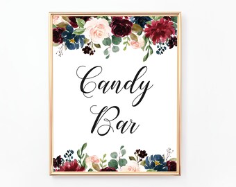 May include: A printable sign with a gold frame and floral border in shades of burgundy, pink, and blue. The sign says "Candy Bar" in a black cursive font.