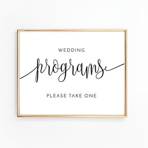 Puede incluir: Un cartel con marco dorado con el texto "Wedding Programs" en escritura cursiva negra. Debajo del texto está la frase "Please Take One" en negro.
