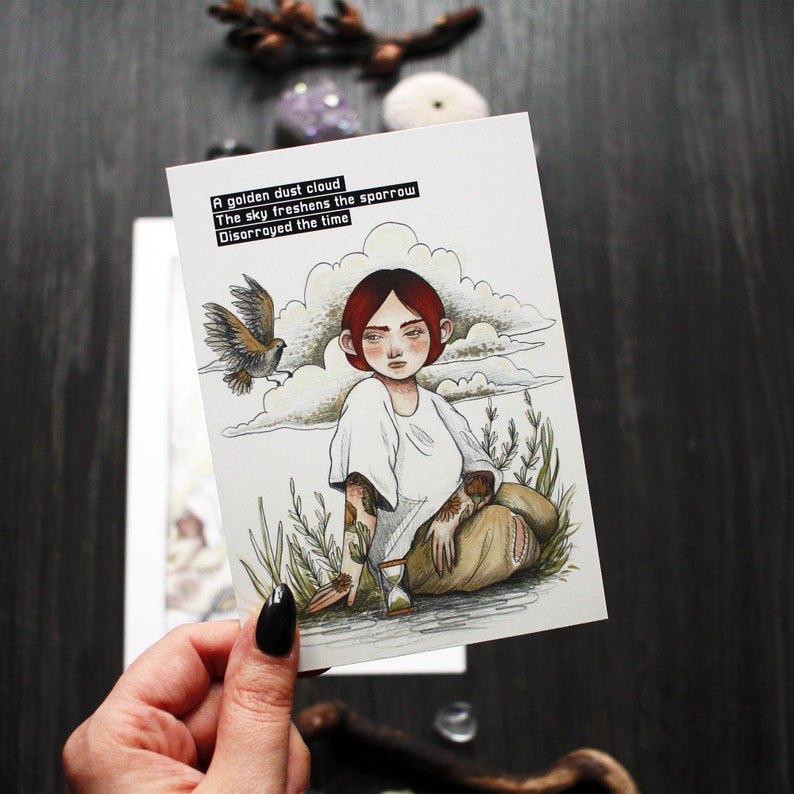 A detailed look at the postcard with the sparrow poem and illustration - Hand for scale.
