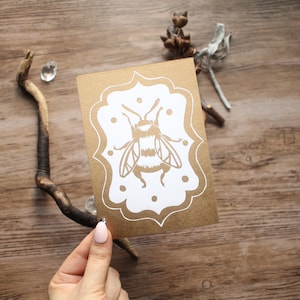 Handgemaakte linosnede kunstafdruk "The Bee" goud op wit - briefkaartformaat