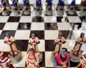May include: A chess set with white and black squares. The pieces are made of painted resin and depict knights in medieval armor. The knights are standing on the board, ready for battle.