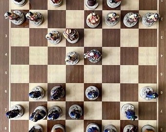 May include: A chessboard with a variety of chess pieces in different positions. The pieces are made of ceramic and have a painted finish. The board is made of wood and has a light brown color.
