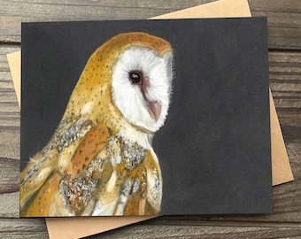 May include: A detailed illustration of a barn owl on a black card. The owl's face is white, with a brown and yellow body. The card is set against a brown background, suggesting a greeting card or art print.