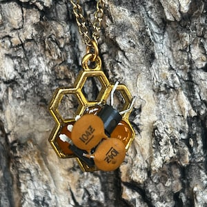 May include: Gold honeycomb pendant necklace with two brown capacitors, one labeled "104Z" and the other "1042".