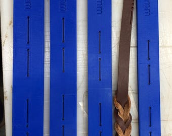 May include: Four rectangular blue plastic leather braiding tools with vertical slots and embossed labels reading 20 mm, 16 mm, 13 mm, and 10 mm, accompanied by a single brown leather strip partially braided into a decorative pattern.