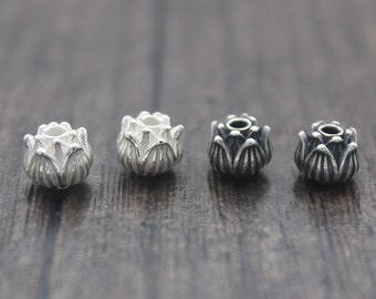 Puede incluir: Cuatro cuentas de plata con forma de flor de loto, dos con acabado pulido y dos con acabado oxidado.