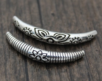May include: Two silver metal beads with decorative floral patterns. The beads are curved and have a smooth, polished finish.