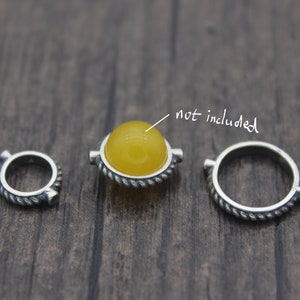 May include: Three silver rings with a rope-like design. The center ring has a yellow gemstone in the center. The text "not included" is written on the image.