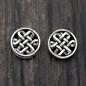 May include: Two silver-toned round earrings with a Celtic knot design.