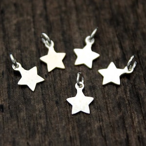 May include: Five silver star-shaped charms with a loop at the top for attaching to jewelry or other crafts.