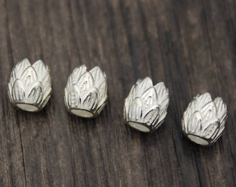 Puede incluir: Cuatro cuentas de plata con forma de flor de loto. Las cuentas son lisas y tienen un diseño detallado.