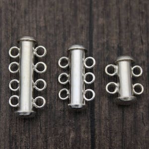 May include: Three silver-toned, multi-strand, toggle clasps for jewellery making. The clasps are different sizes, with the largest clasp on the left and the smallest clasp on the right.
