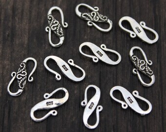 May include: Ten silver-toned metal clasps with intricate designs. Each clasp has a hook and loop closure. The clasps are ideal for jewelry making or other craft projects.