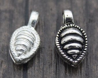 May include: Two silver-toned metal charms in the shape of a beehive. The charms have a detailed design and are perfect for adding a touch of whimsy to jewelry projects.