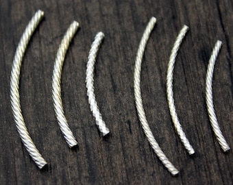 May include: A set of six silver-toned metal wire hoops, each with a different textured finish. The hoops are arranged in a row on a dark wooden surface.