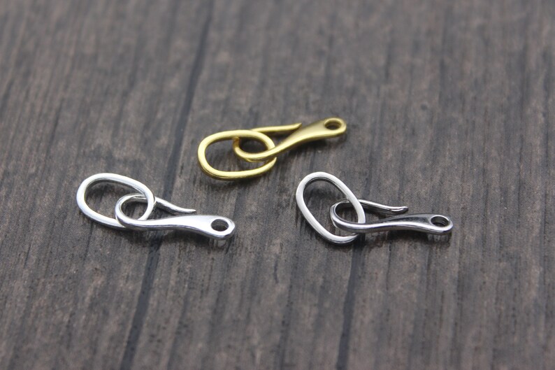 May include: Three metal clasps in different finishes: gold, silver, and nickel. Each clasp has a hook and loop design.