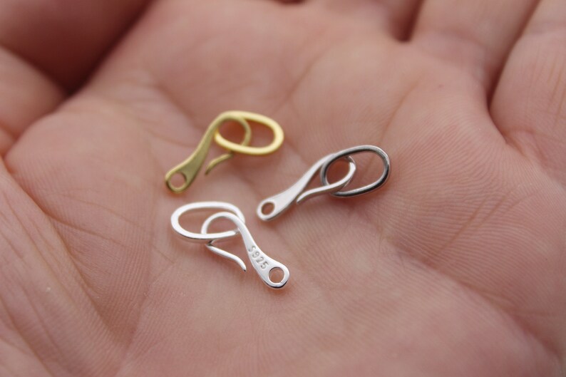 May include: Two silver and one gold lobster claw clasps. The silver clasps are stamped with 925.