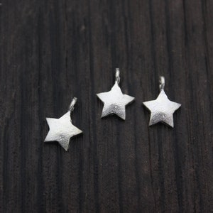 May include: Three silver star-shaped charms with a textured surface.