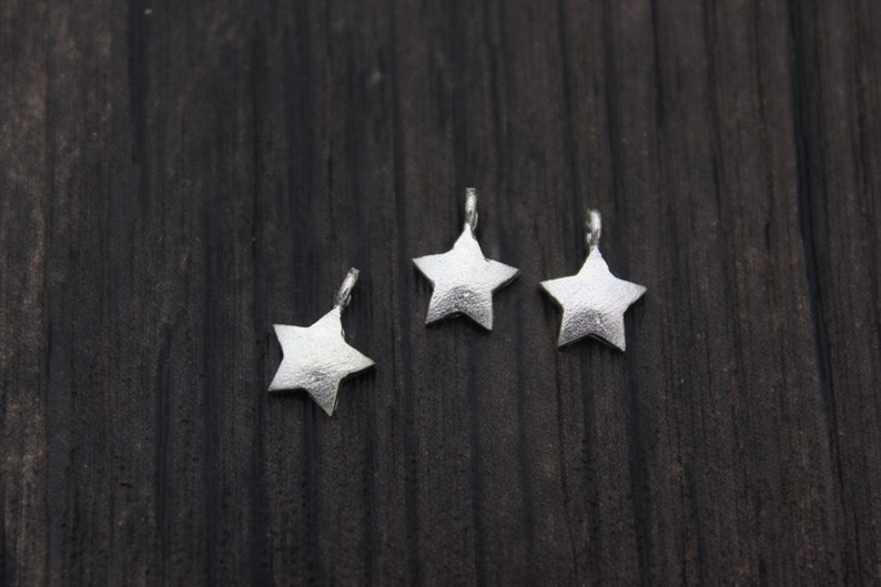 May include: Three silver star-shaped charms with a textured surface.