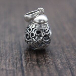 Puede incluir: Un colgante de plata con un intrincado dise&ntilde;o floral. El colgante es redondo y tiene una peque&ntilde;a abertura en la parte superior para una cadena.