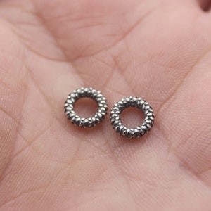 May include: Two silver rings with a textured, diamond-like pattern. The rings are small and delicate.