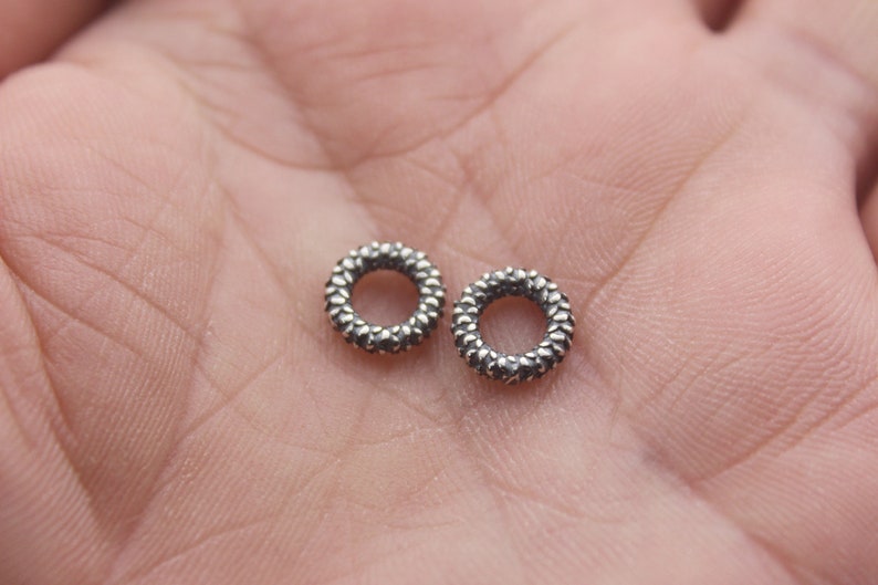 May include: Two silver rings with a textured, diamond-like pattern. The rings are small and delicate.