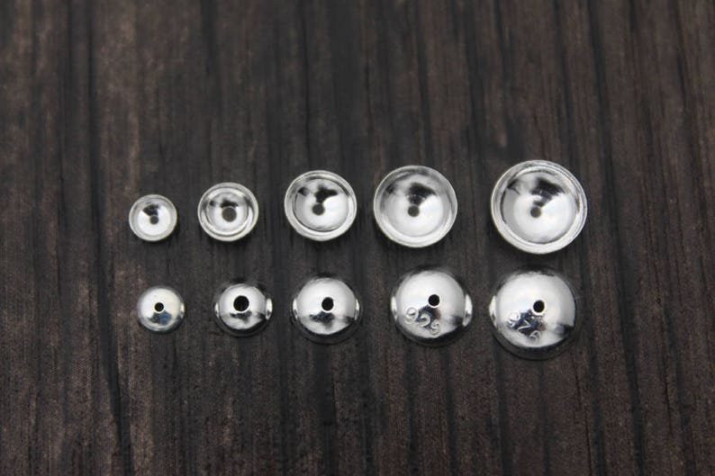 May include: Assortment of silver-toned metal bead caps in various sizes. The caps are round and have a domed shape.