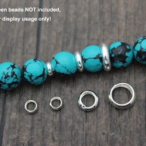 May include: Five silver jump rings of different sizes, with a turquoise and black bead bracelet in the background. Note: The green beads NOT included, just for display usage only!