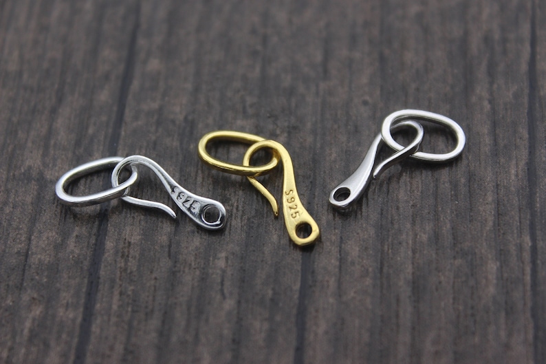 May include: Three silver and gold metal clasps with a hook design. The clasps are marked with the numbers "5925" and "5926".