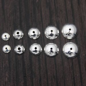 May include: A set of ten silver-toned metal bead caps of varying sizes. The caps are round and have a small hole in the center. The caps are marked with the number "925" indicating they are made of sterling silver.