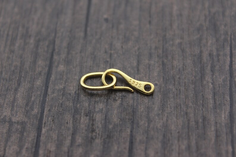 May include: Gold-toned metal clasp with a hook and a loop. The clasp is marked with the text "S925".