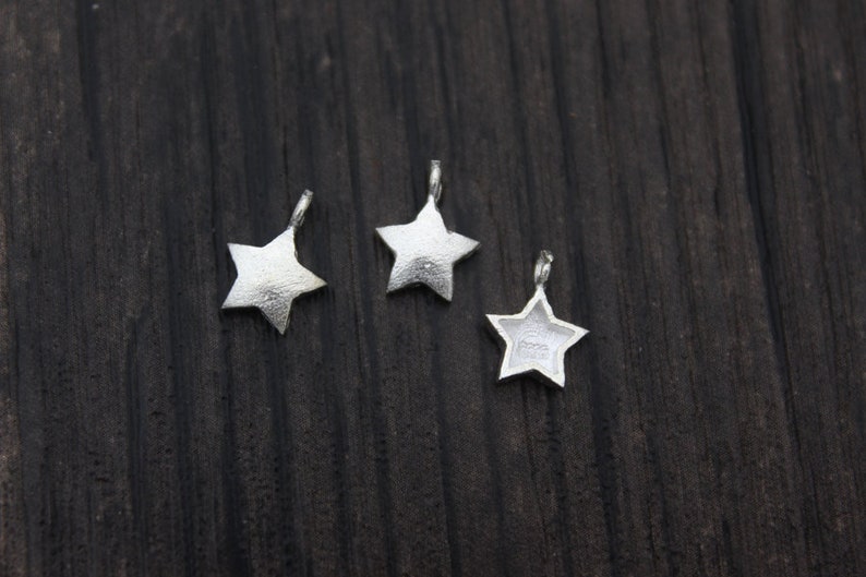 May include: Three silver star-shaped charms with a loop at the top for attaching to jewelry or other crafts.