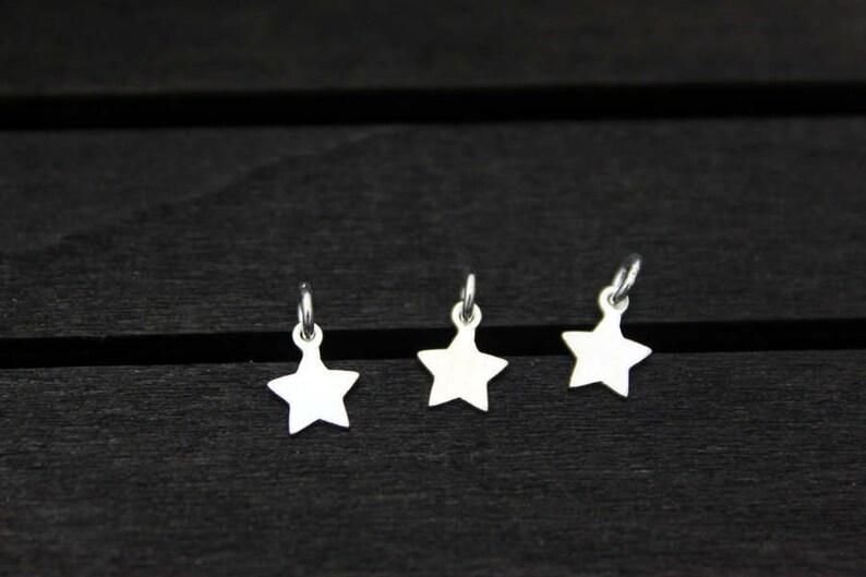 May include: Three silver star-shaped charms with a loop at the top.