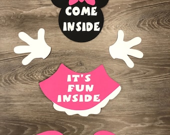 May include: A black and white Minnie Mouse head cutout with a pink bow and the text "Come Inside". There is a pink skirt with white trim and the text "It's Fun Inside". There are two pink hands and two pink shoes.