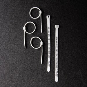 Pode incluir: Tr&ecirc;s calibradores de anel de pl&aacute;stico branco e duas fitas m&eacute;tricas de tamanho de anel de pl&aacute;stico branco. As fitas s&atilde;o marcadas com "SIZE & HALF SIZES" e n&uacute;meros de 1 a 17. As fitas s&atilde;o marcadas com "PAT, PEND. 9101693".