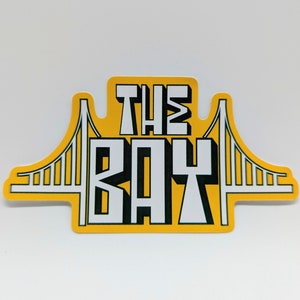 May include: Yellow sticker with a black and white graphic of the Golden Gate Bridge and the text "THE BAY".