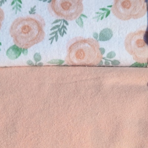 May include: Two pieces of fabric, one with a white background and a peach floral pattern, and the other a solid peach colour.