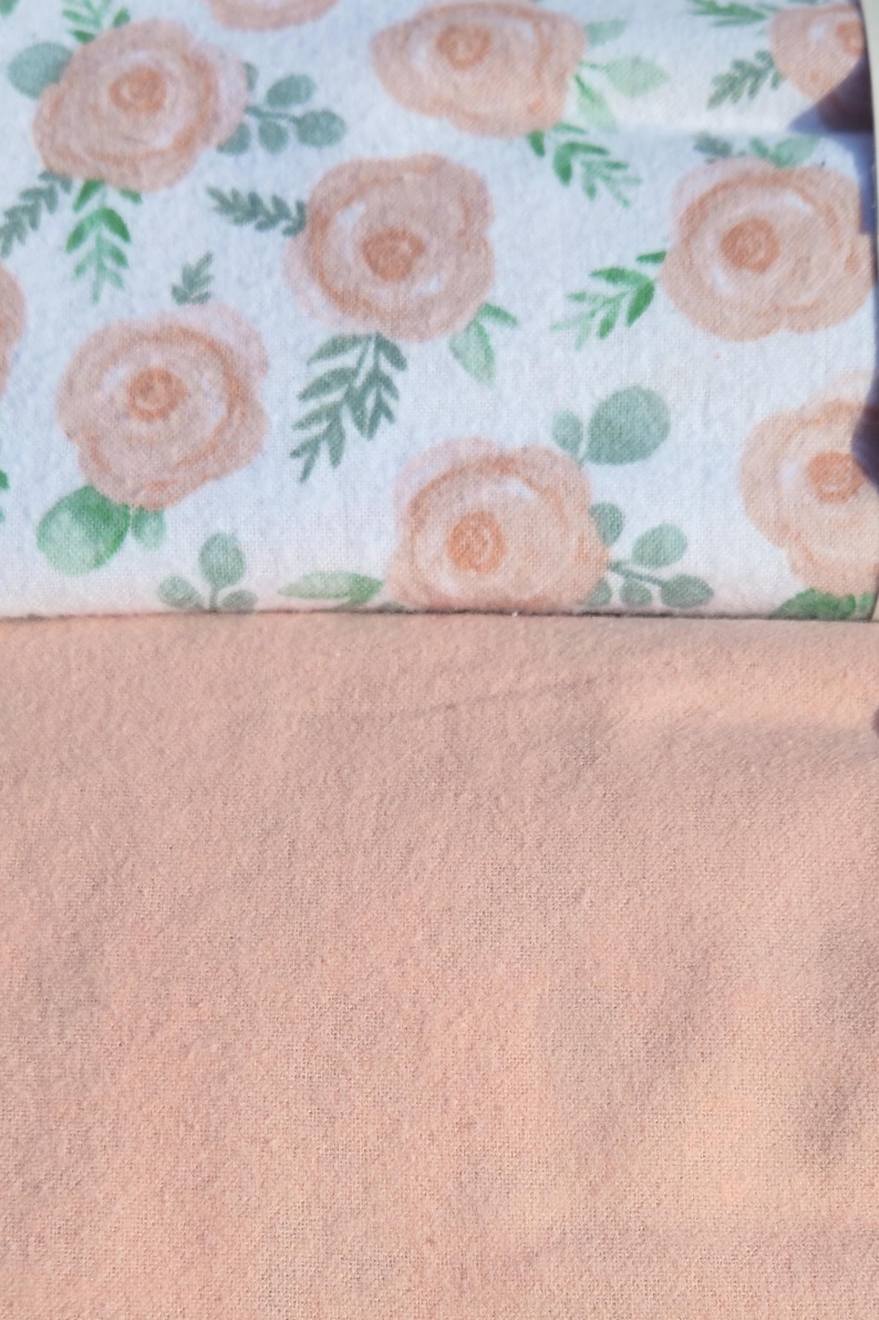 May include: Two pieces of fabric, one with a white background and a peach floral pattern, and the other a solid peach colour.