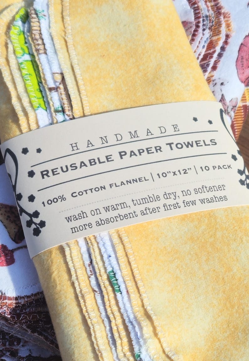 May include: A stack of 10 handmade reusable paper towels made from 100% cotton flannel. The towels are yellow and white with a brown label that reads "HANDMADE REUSABLE PAPER TOWELS 100% COTTON FLANNEL | 10"x12" | 10 PACK wash on warm, tumble dry, no softener more absorbent after first few washes".