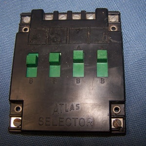 May include: A black Atlas selector switch with four green toggle switches labeled A and B. The switch is labeled "ATLAS SELECTOR".
