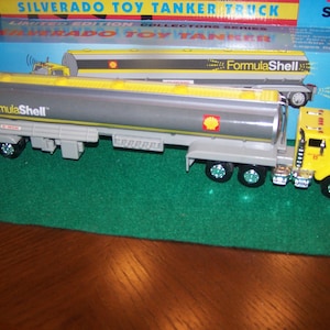 May include: A gray and yellow toy tanker truck with the words "FormulaShell" on the side. The truck is a limited edition collector's series Silverado toy tanker truck.