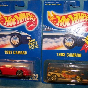 May include: Two Hot Wheels 1993 Camaro die-cast model cars on blue packaging. One is red, the other is black and white. The packaging features the Hot Wheels logo and the text "1993 Camaro".