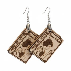May include: A pair of dangling earrings featuring rectangular wooden charms with a laser-engraved illustration of Snow White holding an apple. The text "Snow White" is etched at the top of each charm. The earrings have silver-toned metal hooks.