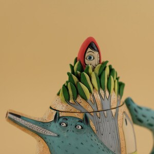 May include: A ceramic teapot with a wolf design and a red hooded girl peeking out from the top of the teapot.