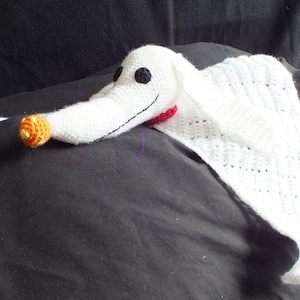 May include: White crocheted plush toy shaped like Zero, the ghost dog from the Nightmare Before Christmas, with a red collar and orange pumpkin.