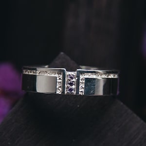 Peut inclure: Une alliance en argent avec un design unique comprenant une rangée de petites pierres précieuses violettes serties dans la bande.