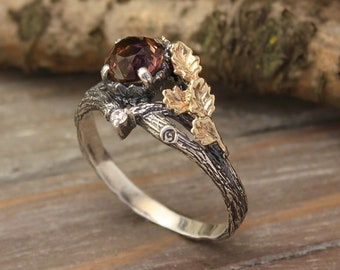 May include: A silver ring with a brown gemstone set in a branch design. The ring features gold leaves on the branch.